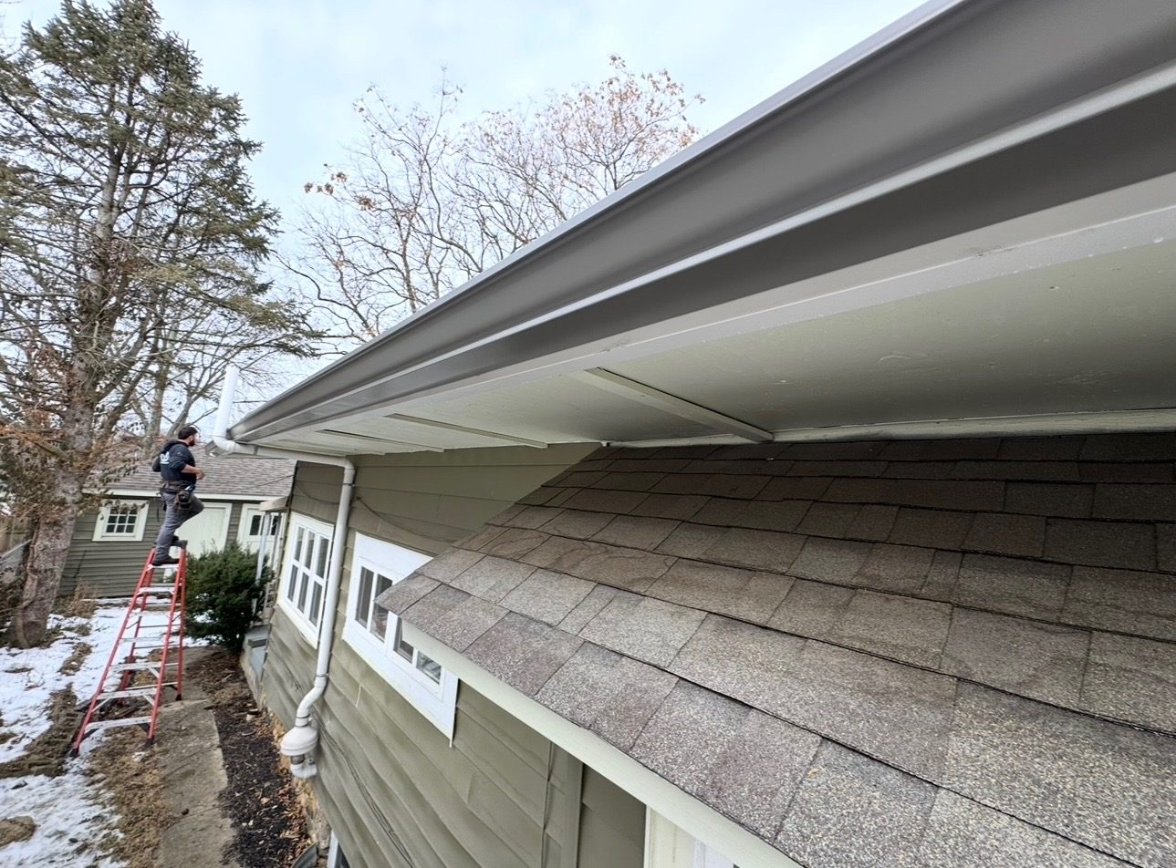 Bryant worker on a ladder installing gutter along a roof edge